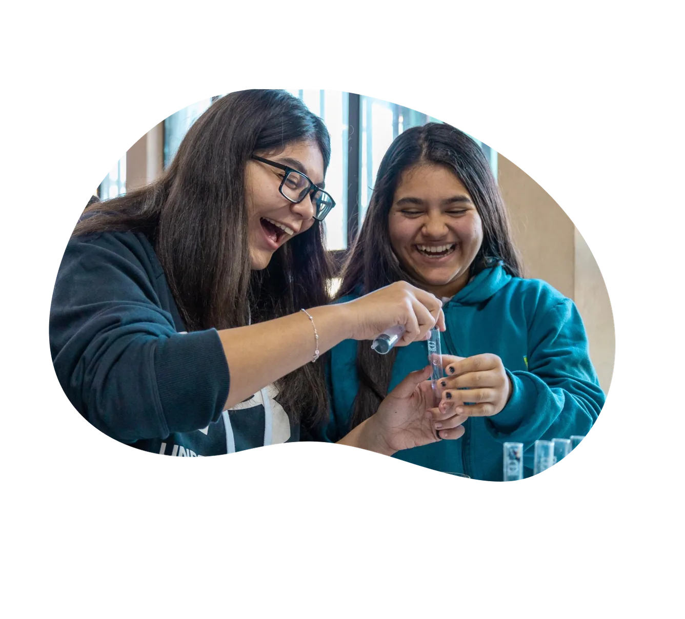 Dos estudiantes riendo mientras hacen un experimento con tubos de ensayo